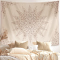  A large, flaxen-colored floral mandala wall tapestry hanging above a bohemian-style bed with neutral-toned linens and dried pampas gr